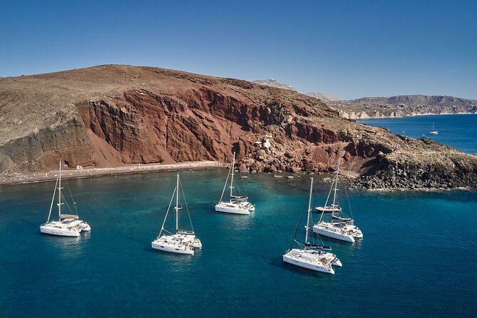 Santorini: Luxury Catamaran Cruise with Fresh Fish BBQ & Drinks - Red Beach, seen from the turquoise water