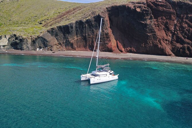 Santorini: Luxury Catamaran Cruise with Fresh Fish BBQ & Drinks - The lighthouse and the southern tip of Santorini